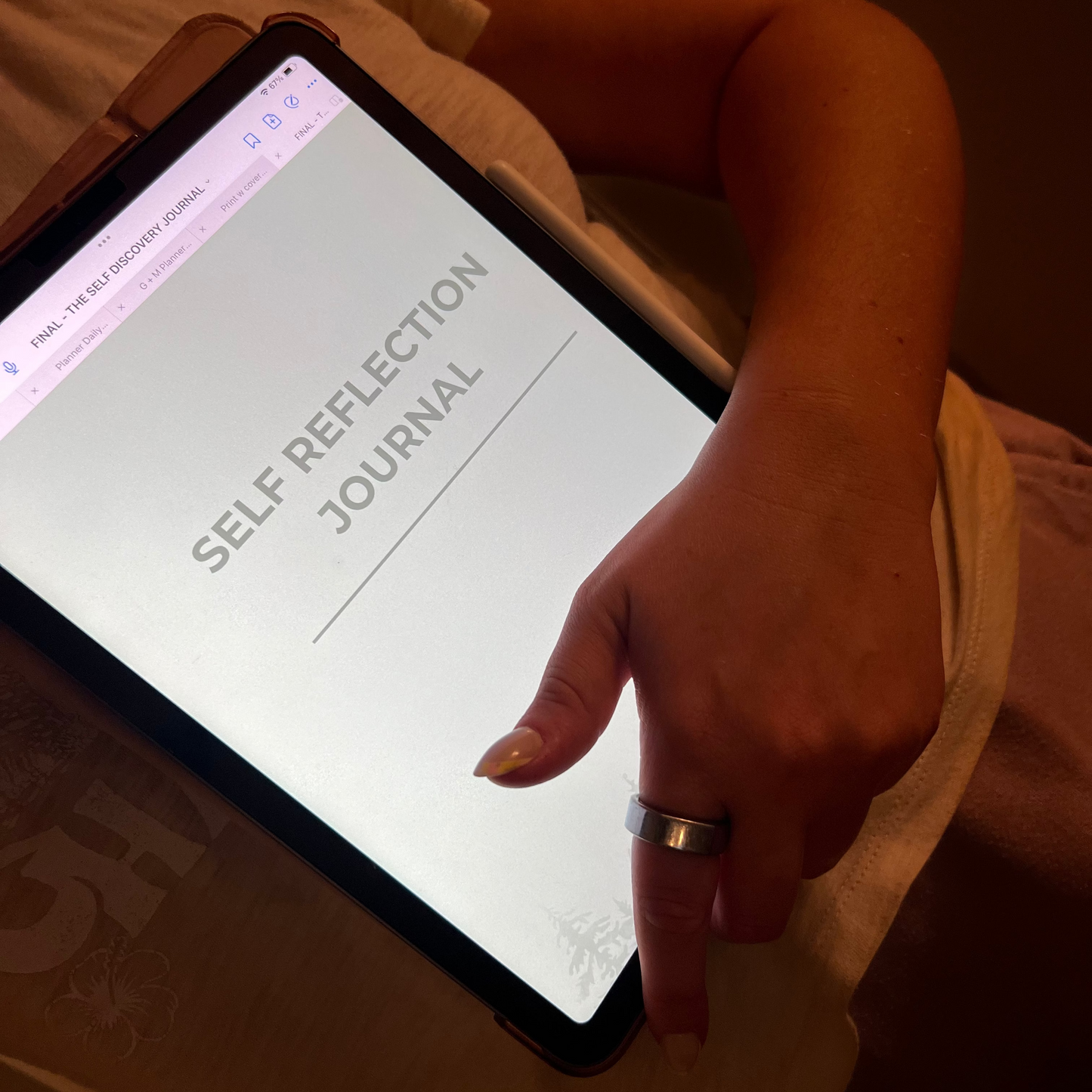 Person using a tablet with a 'Self Reflection Journal' app on a dimly lit surface.