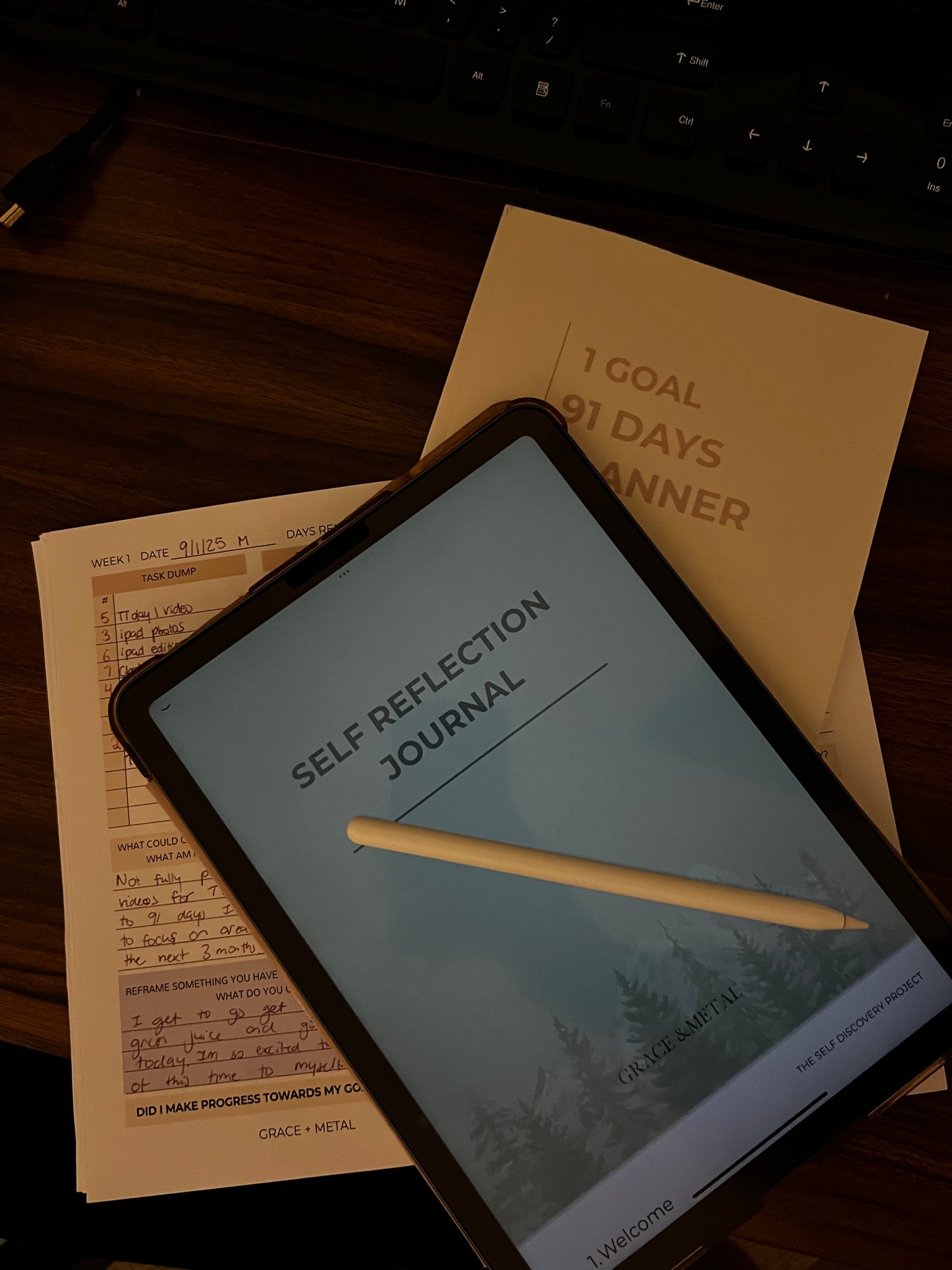 Digital tablet displaying a 'Self Reflection Journal' app on a desk with a planner and pen.